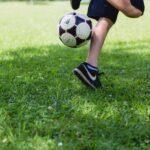 A child skillfully kicks a soccer ball on a sunny day, showcasing outdoor activity and fun.