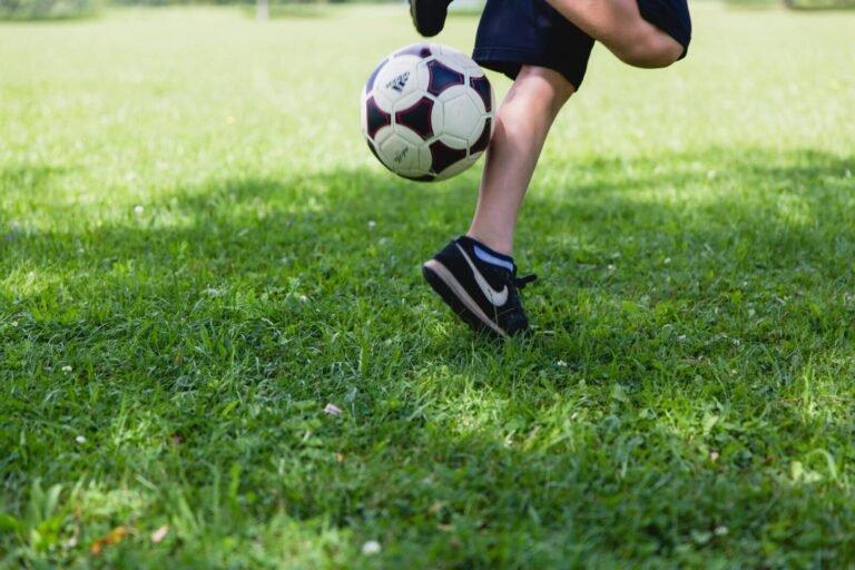 A child skillfully kicks a soccer ball on a sunny day, showcasing outdoor activity and fun.