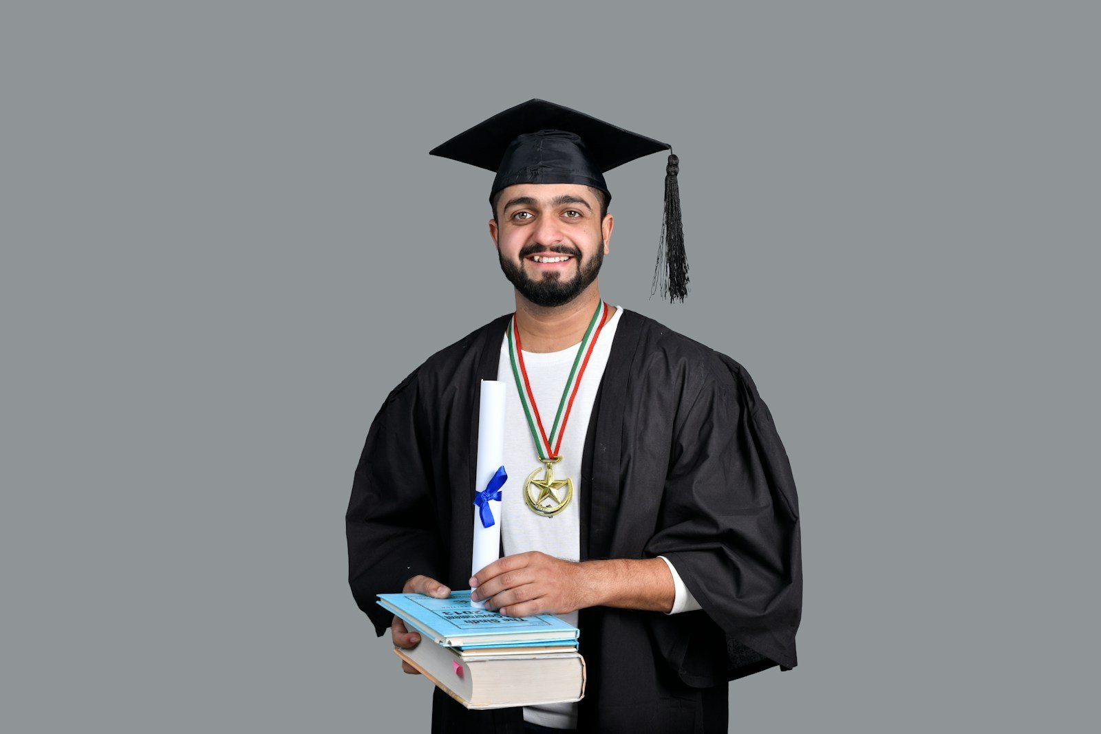 a man wearing a graduation cap and gown holding a book
